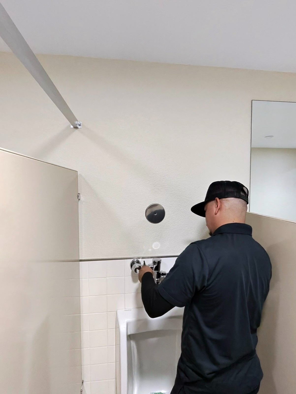 Plumber servicing a commercial urinal